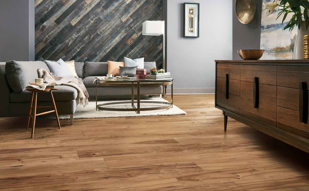 mid-tone hardwood flooring in modern Living Room with gray sectional, gray plank accent wall and cozy layers